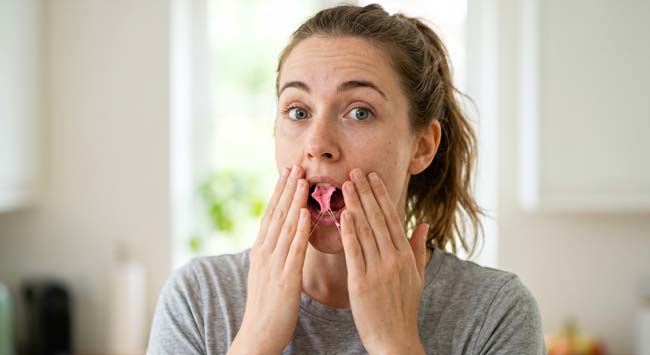 A woman accidentally swallowing chewing gum with a surprised expression illustrating the common experience and the science of what happens when gum enters the digestive system