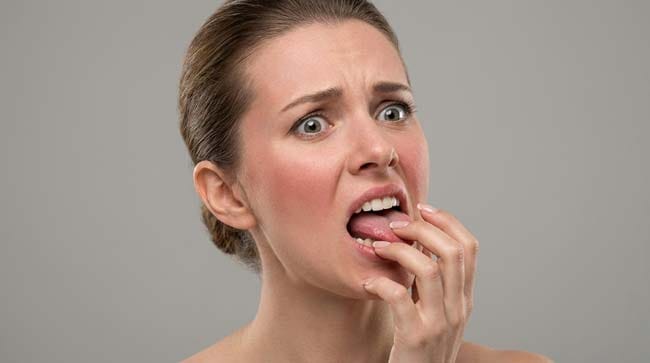A woman wincing in pain and touching her mouth after accidentally biting her tongue illustrating the intense nerve pain caused by high sensory receptor density in the tongue
