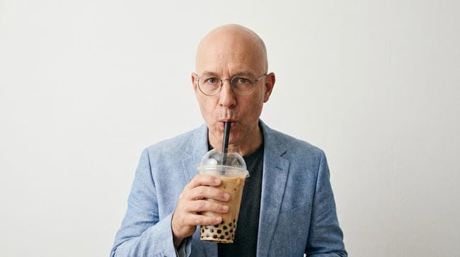 A person looking shocked while holding a large bubble tea surrounded by empty cups illustrating what happens when you drink too much bubble tea including blood glucose spikes insulin resistance liver fat accumulation and metabolic syndrome risk